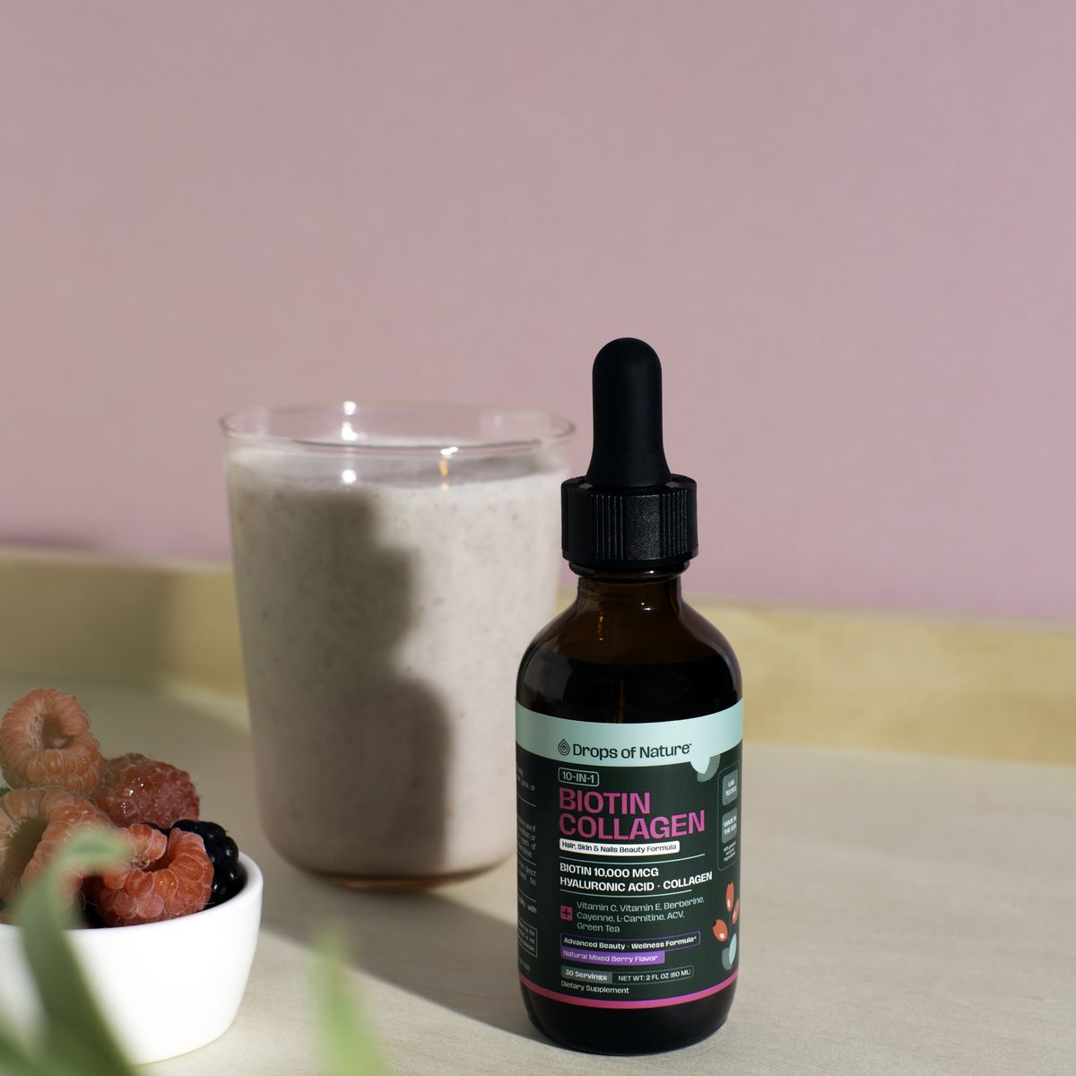 Biotin Collagen bottle beside a smoothie and a small bowl of berries.