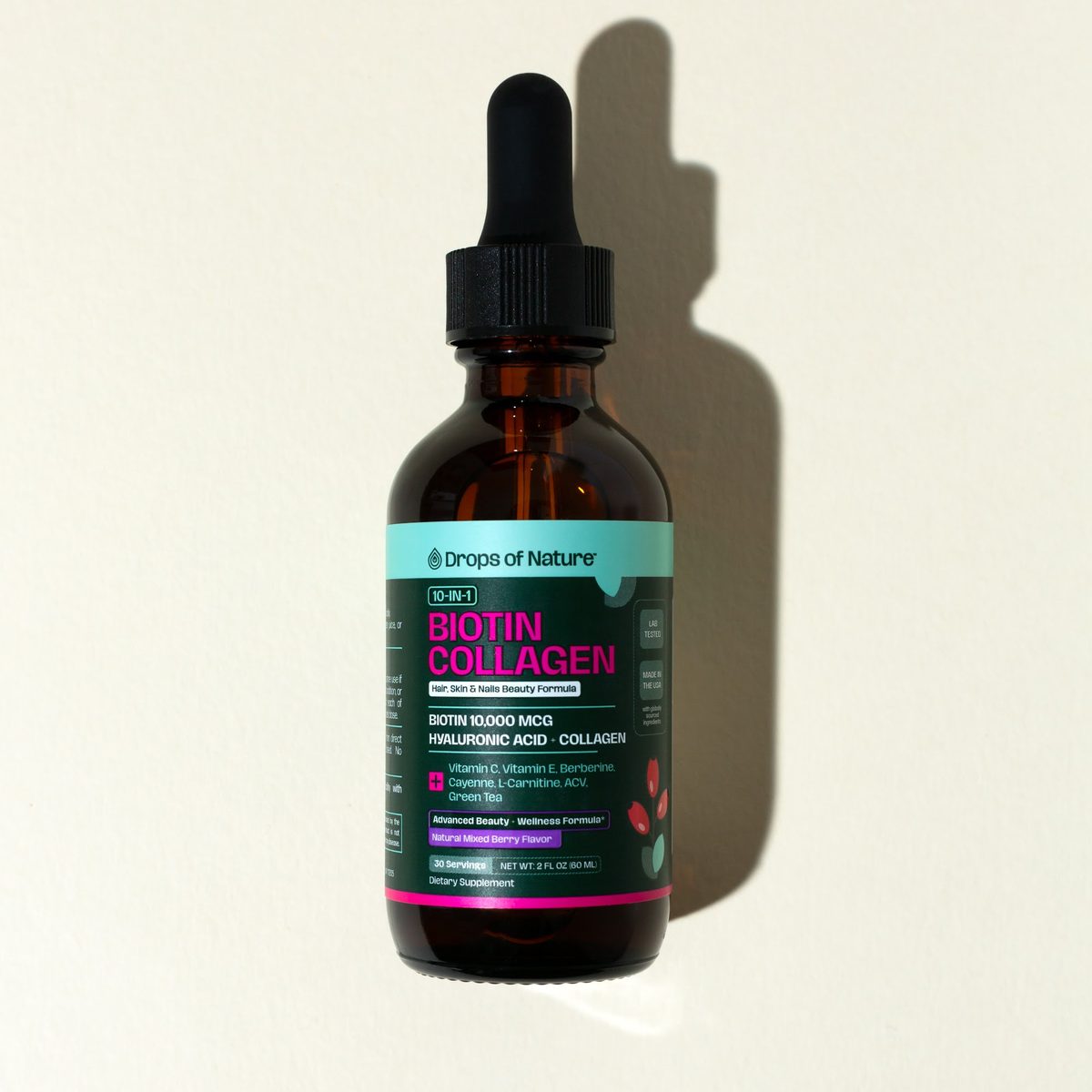 Biotin Collagen bottle and box with berries on a pink backdrop.