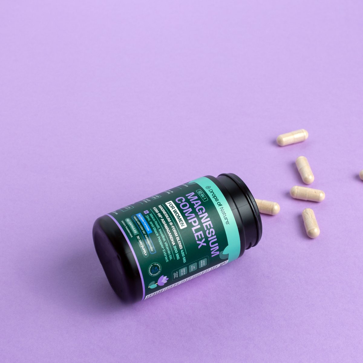 Magnesium Complex bottle on its side with capsules on a lavender backdrop.
