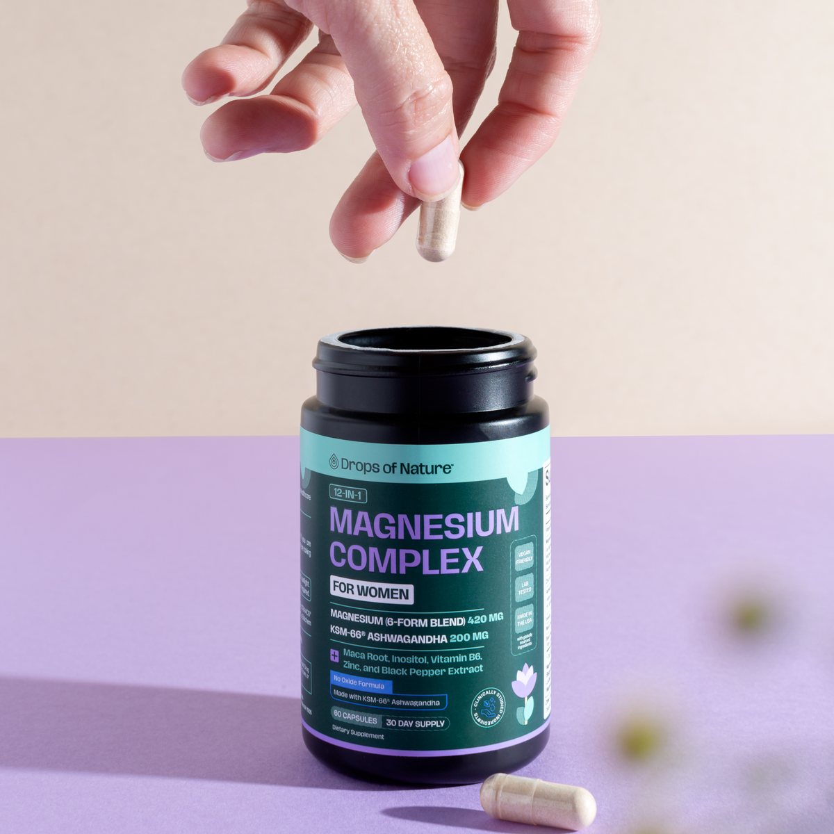 A hand dropping a capsule into an open bottle of Magnesium Complex.