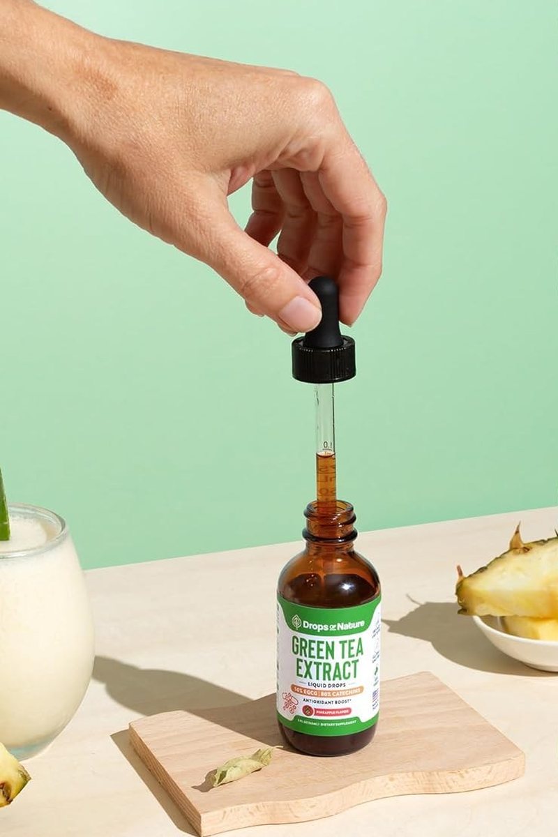 A hand filling the dropper from a bottle of Green Tea Extract drops.