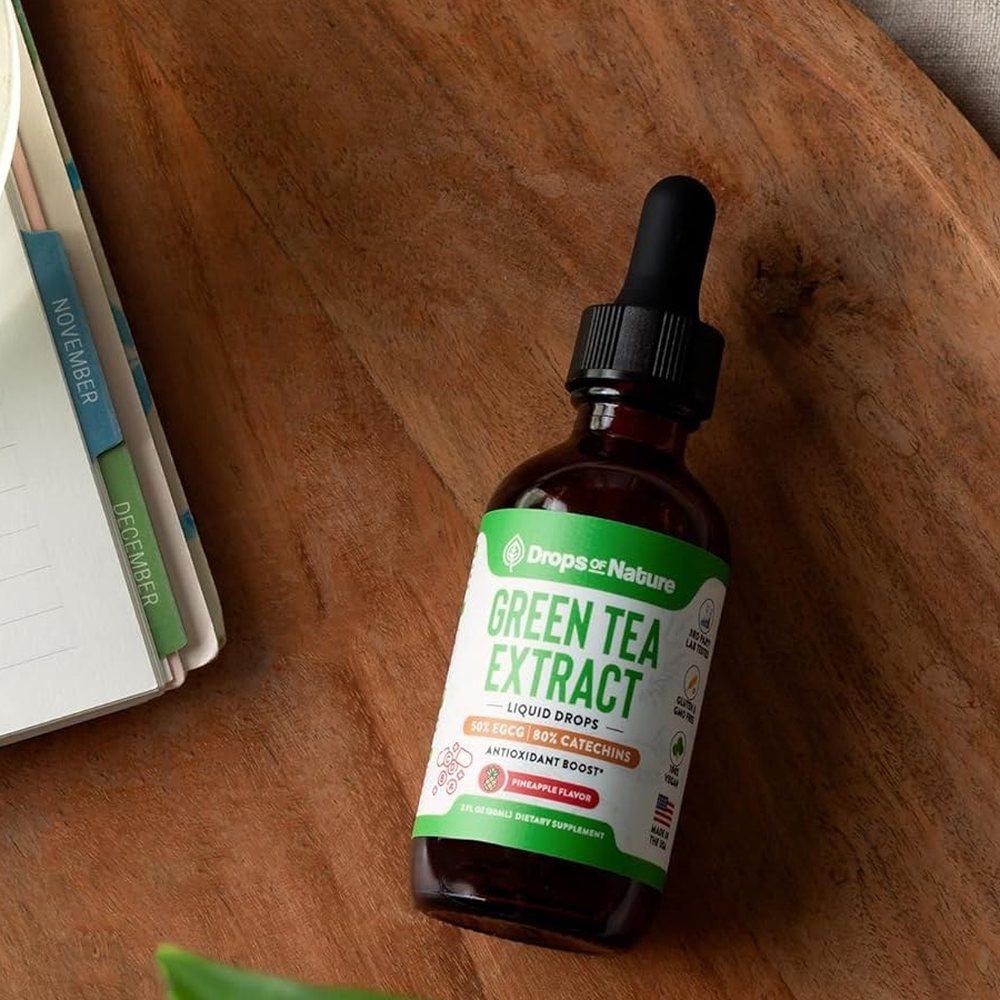 Green Tea Extract bottle on a wooden board beside a notebook.