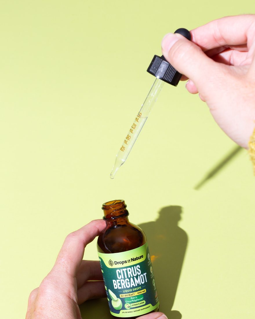A hand holding a bottle of Citrus Bergamot drops