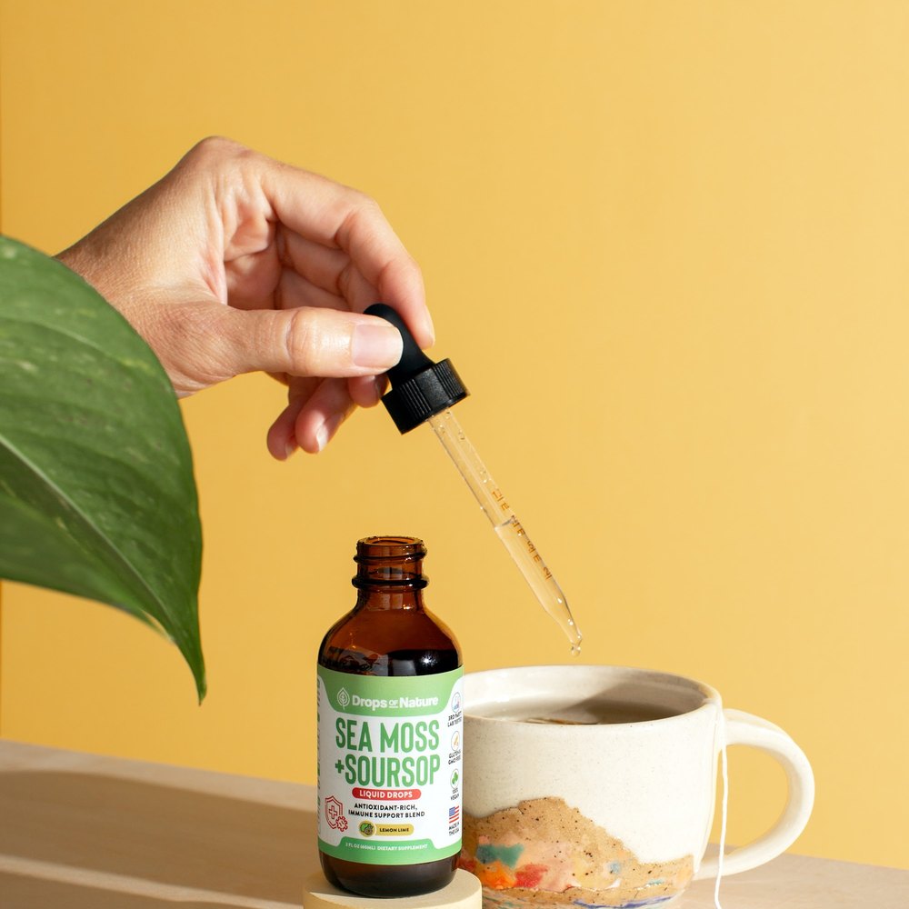 Soursop + Sea Moss drops beside a mug of tea with lemon.