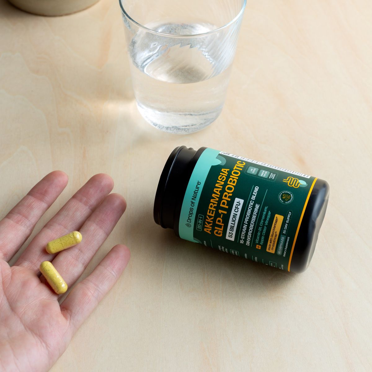 Hands with the Akkermansia GLP-1 Probiotic bottle and capsules.