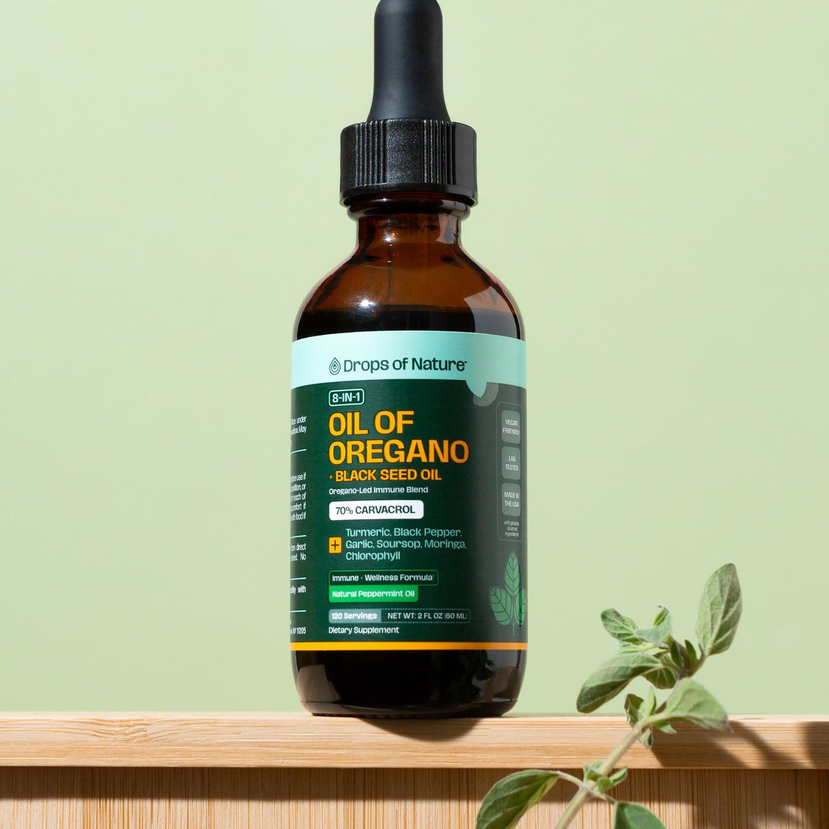 Drops of Nature 8-in-1 Oil of Oregano + Black Seed Oil, 2 fl oz bottle with a fresh oregano sprig.