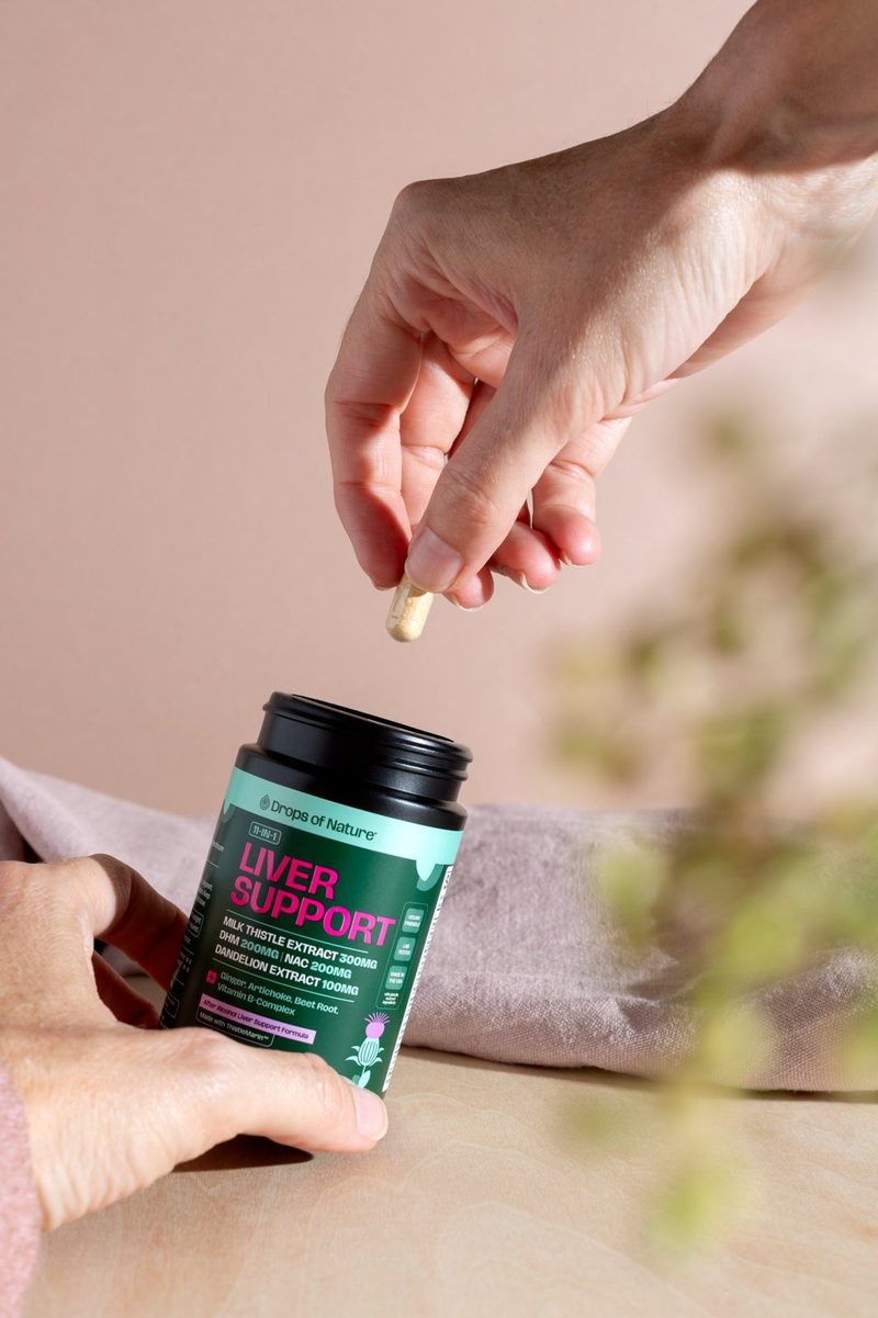 A hand taking a capsule from a bottle of 11-in-1 Liver Support