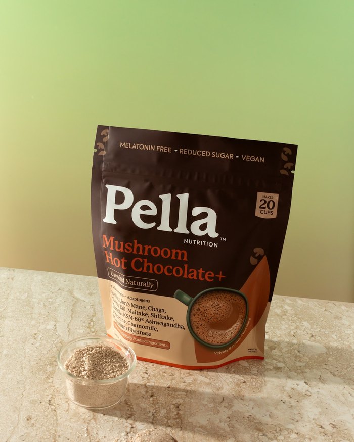 A spoonful of cocoa powder held above the Mushroom Hot Chocolate bag