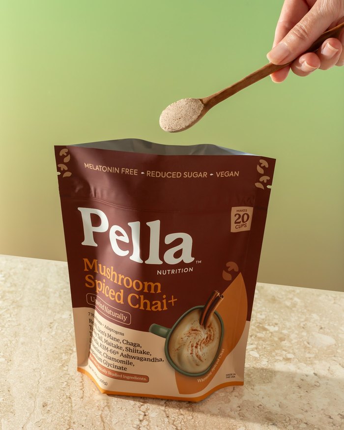A hand holding a spoonful of chai powder over the Spiced Chai bag